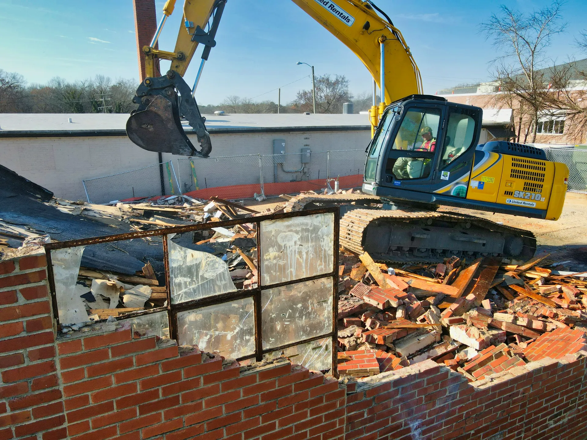 Excavadora demoliendo un edificio de ladrillo